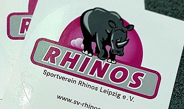 Aufkleber mit dem Logo des SV Rhinos Leipzig. Graues laufendes Nashorn in einem roten Halbkreis über dem Schriftzug RHINOS