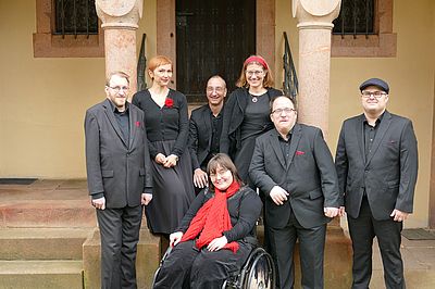 Gruppenfoto der Mitglieder der Thonkunst vor der St. Gangolf-Kirche in Kohren-Salis. Die Mitglieder tragen alle schwarze Kleidung mit roten Accessoires.