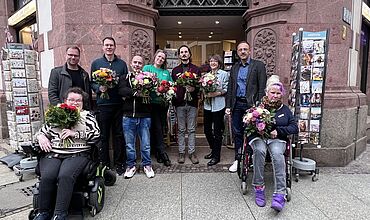 Gruppenbild der Mitarbeitenden vom Nikolai-Eck mit Blumensträußen vor dem Laden